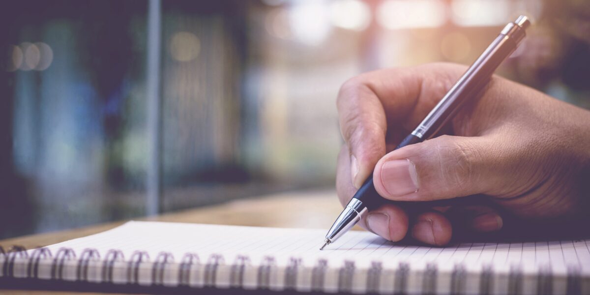 Professional making notes during a business conversation about media and communications.